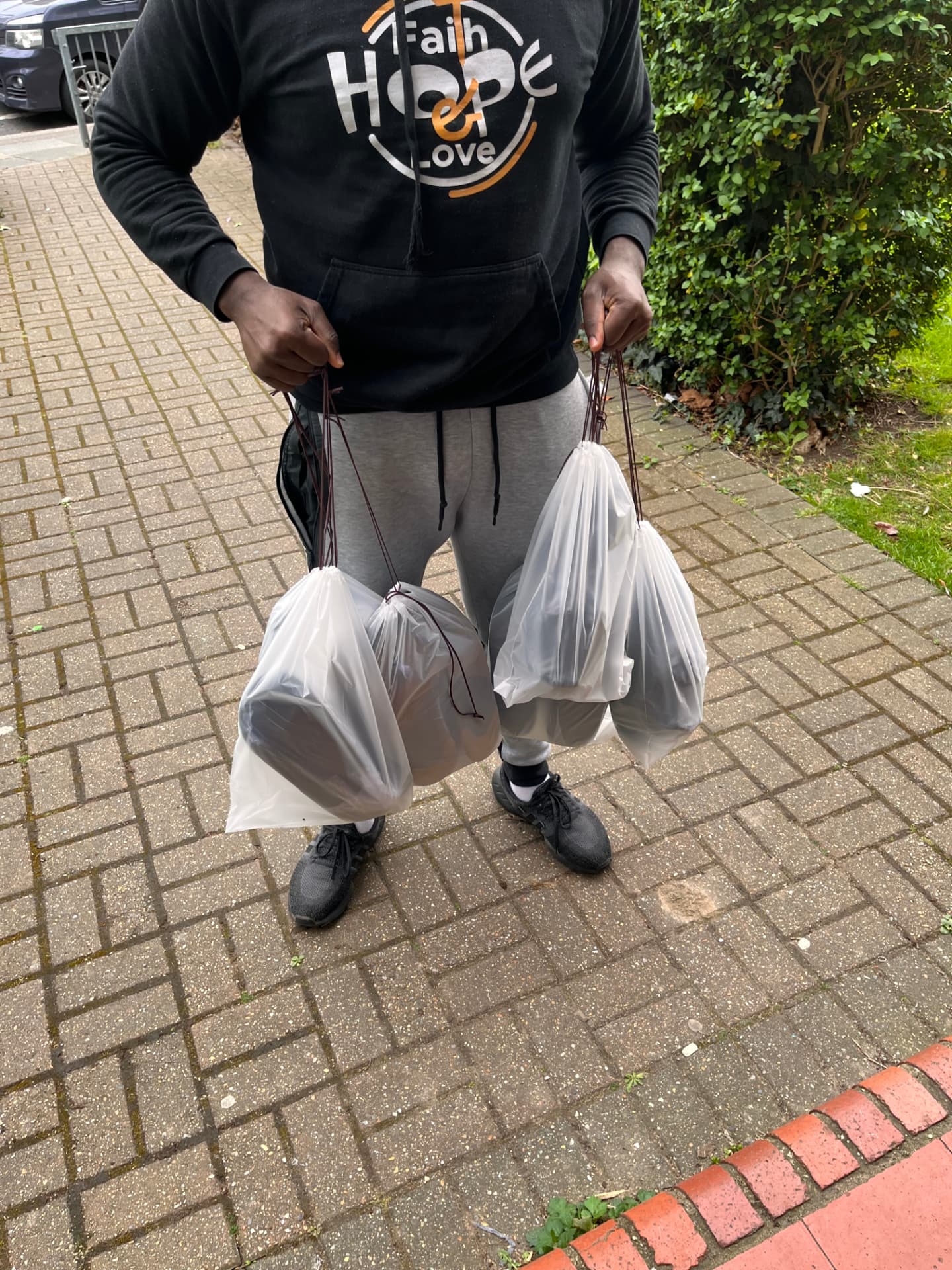 Client holding four bags of freshly cleaned sneakers